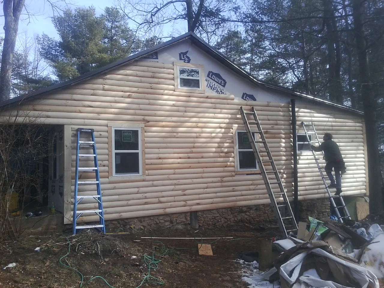 Ladders set against fresh log siding during an exterior remodel in Auburn